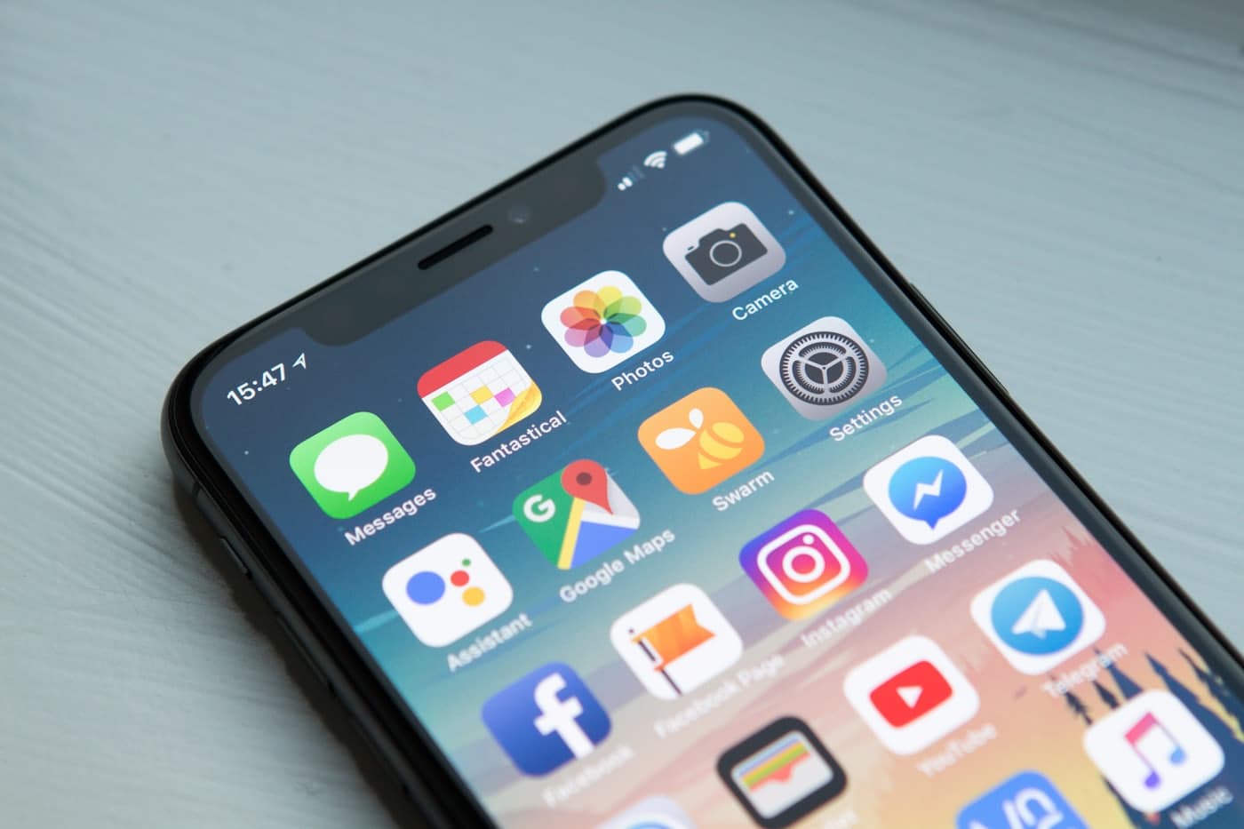 A smartphone home screen held in one hand, showing common apps including Google Maps.